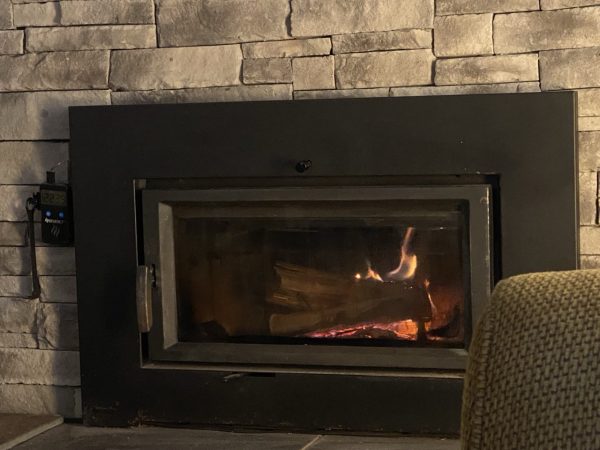 Insert fireplace in a stone surround. A couple of logs burning.